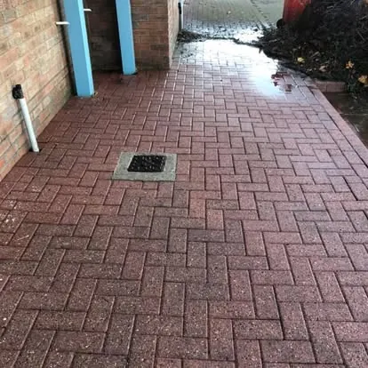The same commercial block-paved passage after pressure washing, paving restored to red